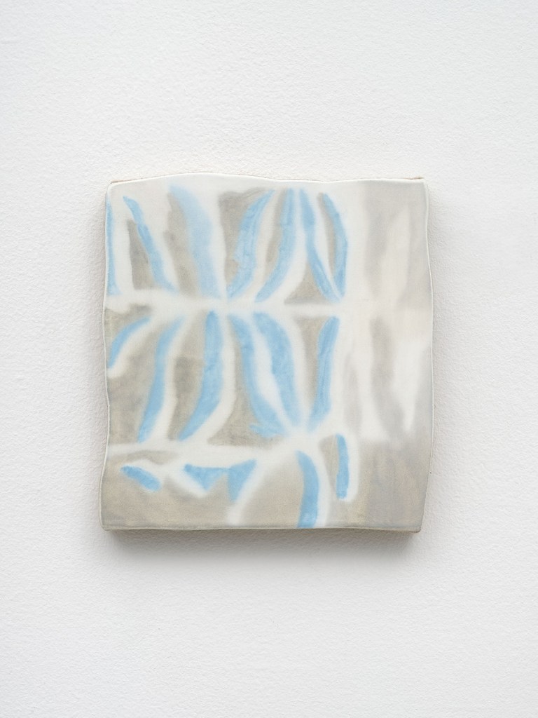 A square ceramic wall art piece featuring abstract patterns in light blue and gray on a white background.