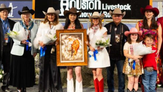 Group of individuals in cowboy hats and Western attire posing with awards and flowers at a livestock event.