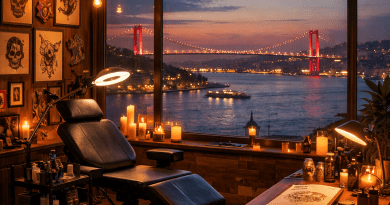 Tattoo studio interior with chair, equipment, and large window showing illuminated suspension bridge over water at sunset