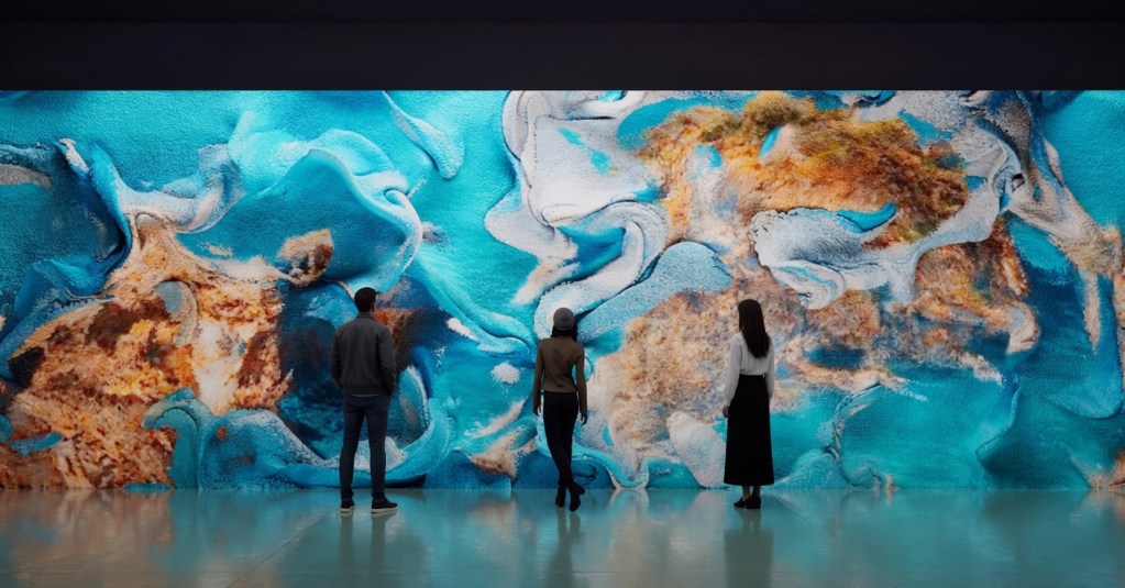Three people observing a large, colorful abstract mural featuring vibrant blue hues and earthy textures.