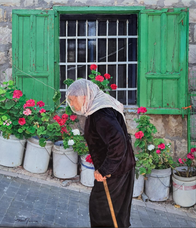 An elderly woman wearing a headscarf and black clothing walks with a cane in front of a stone wall and a green wooden window surrounded by colorful flowers in pots.