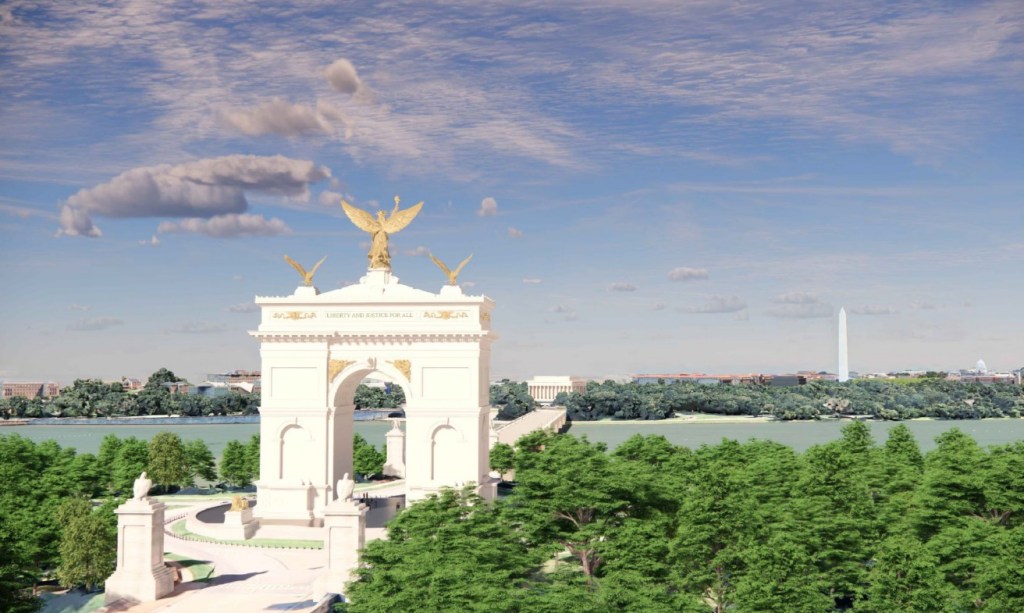 Aerial view of a grand monument with an angel statue on top, inscribed with 'Liberty and Justice for All', surrounded by lush greenery and a river. In the background, the Washington Monument is visible under a blue sky with clouds.