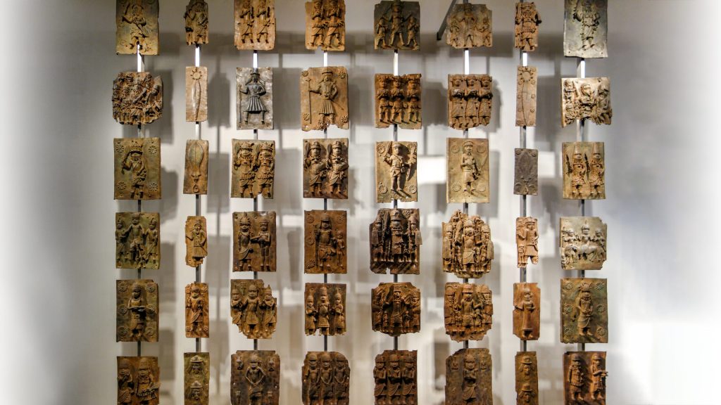 A wall display featuring numerous carved stone reliefs, showcasing intricate designs and figures from ancient cultures.
