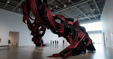 Large abstract sculpture made of red and black fabrics and metal in a spacious gallery
