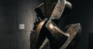 Abstract bronze sculpture with geometric shapes in a gallery setting