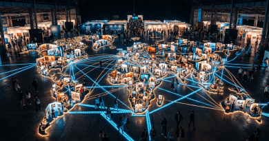 Large illuminated world map installation with art booths and visitors indoors