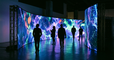 Five people walking and observing a curved digital screen with colorful abstract visuals