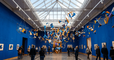 Gallery with hanging abstract sculptures and people viewing art