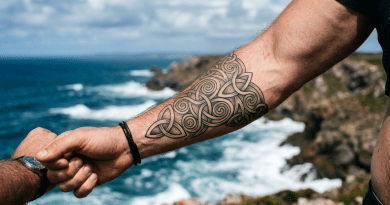 Outstretched arm with Celtic tattoo holding another hand near coastal cliffs