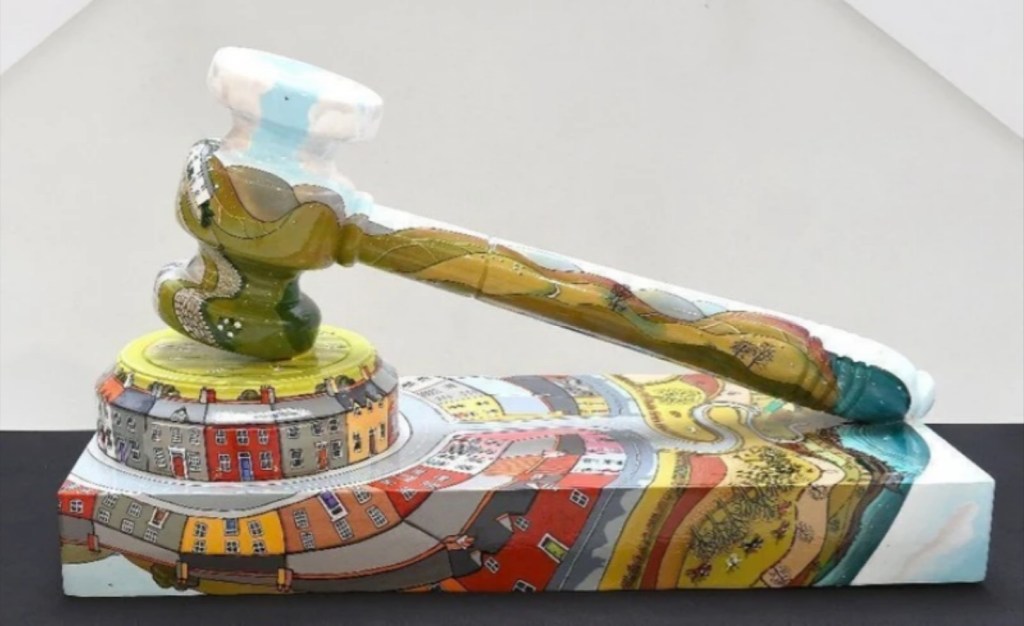 Colorful sculptural gavel with landscape design on a black base, representing artistic interpretation of auction traditions.

