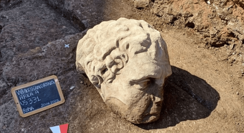 Ancient Roman marble head with curly hair and beard, recently discovered in archaeological excavations at the Basilica of Santo Stefano, Rome, 2026.


