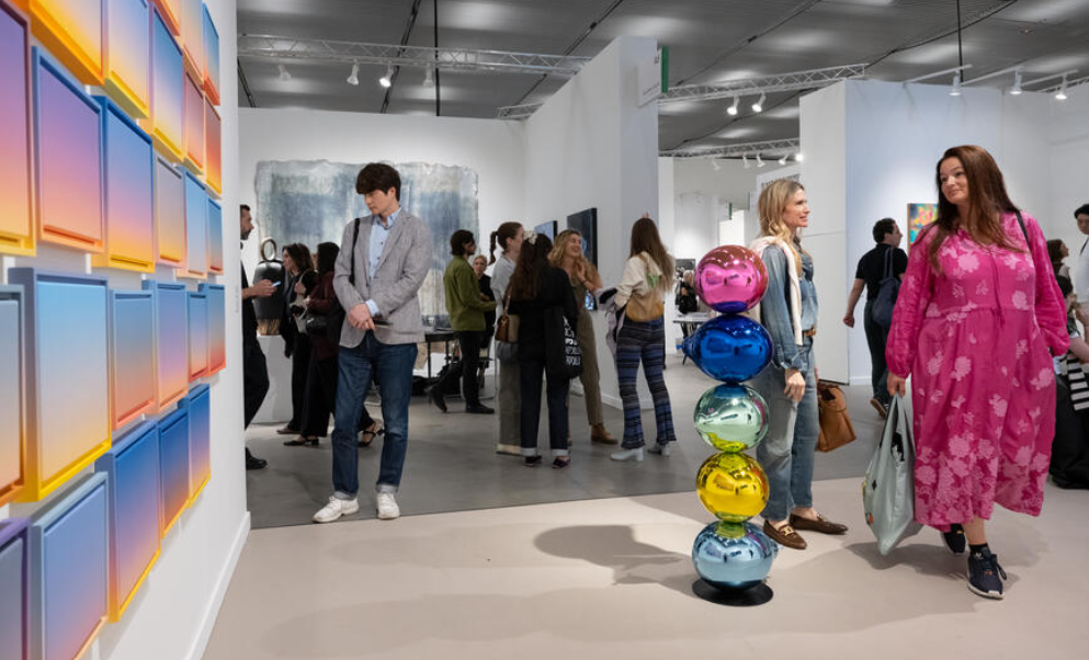  Visitors examining colorful artworks and sculptures at Frieze New York fair booths.
