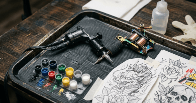 Tattoo machine, color ink pots, and tattoo design sketches on tray