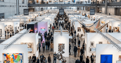 Interior view of a contemporary art fair with numerous booths and visitors