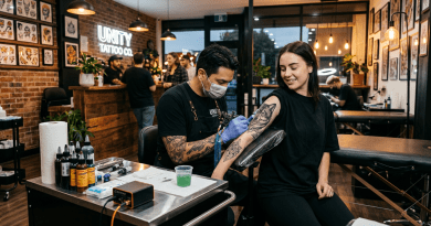 Tattoo artist applying a large owl and geometric tattoo on woman’s upper arm