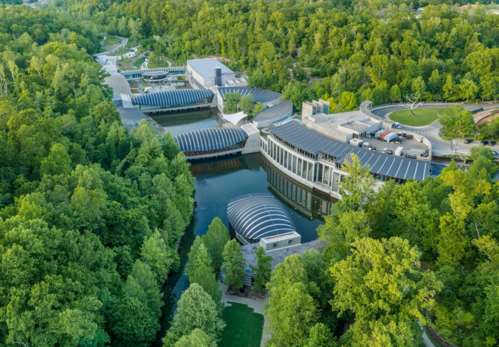 Aerial photograph of Crystal Bridges Museum of American Art in Bentonville, Arkansas, with modern architecture nestled among green trees and ponds.