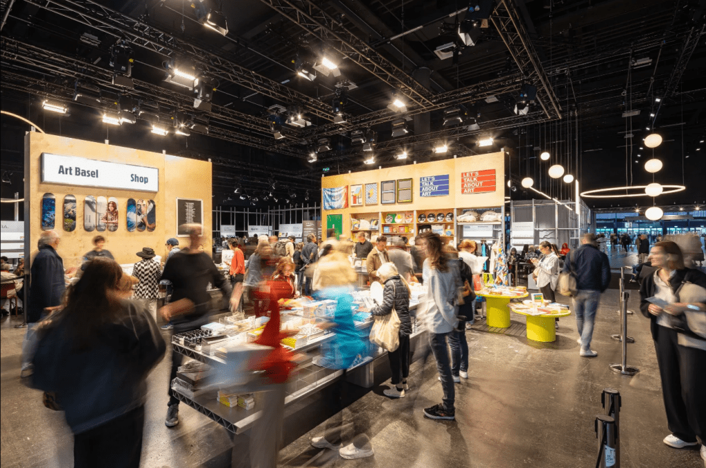 Busy Art Basel gift shop interior with attendees browsing merchandise and displays during the 2026 fair in Basel, Switzerland.