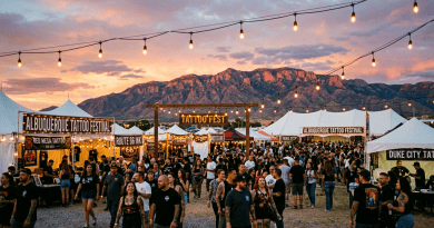 Crowd walking among booths at Albuquerque Tattoo Festival during sunset with mountain in background