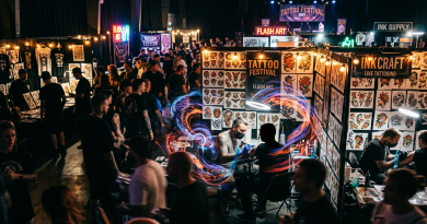 Tattoo artists working on clients at live tattooing booths surrounded by colorful flash art at a crowded tattoo festival